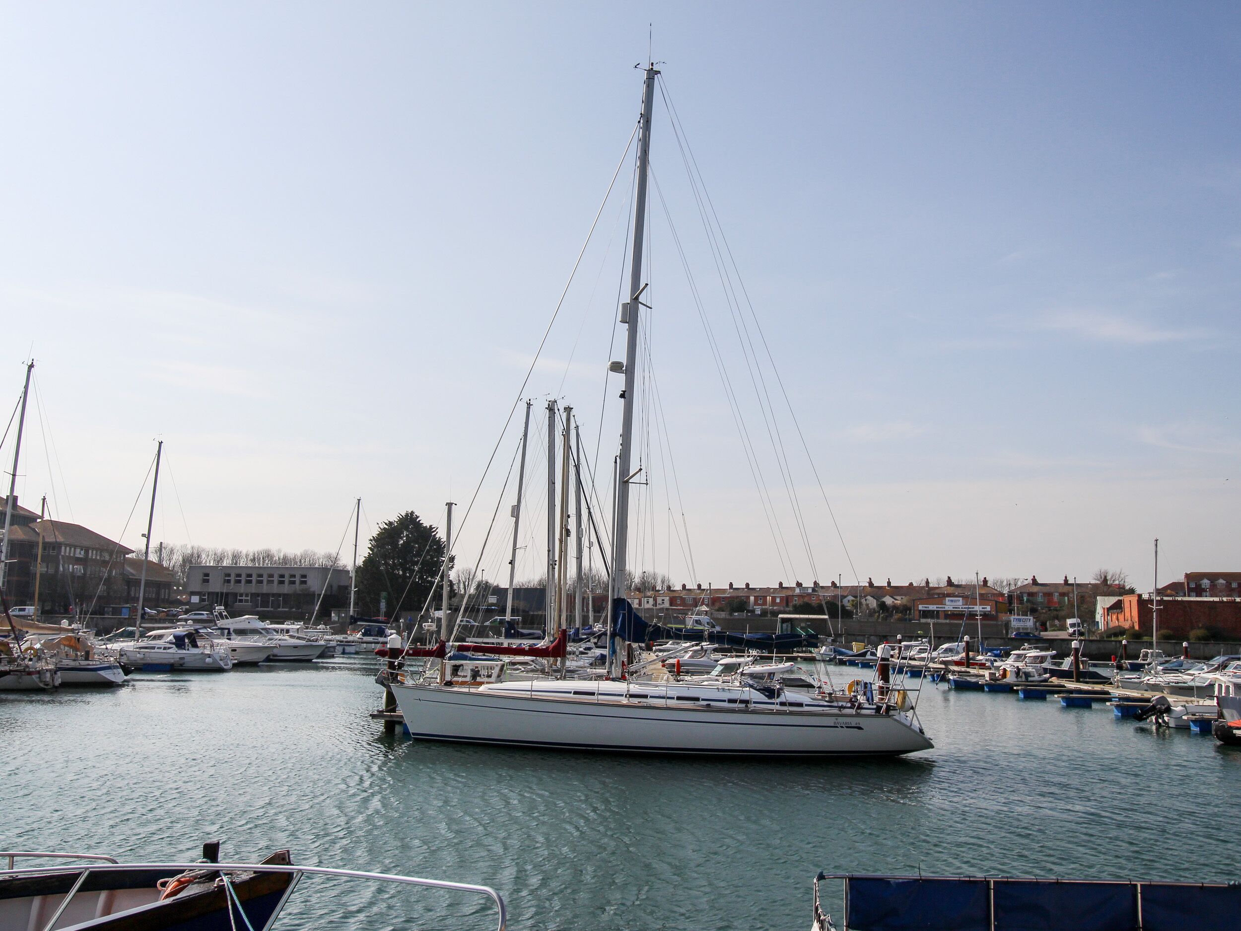A marina with various boats docked, including a large sailboat and several smaller vessels.