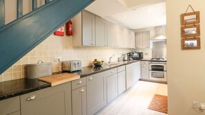 A modern kitchen with grey cabinets, a black countertop, a toaster, a kettle, and a stove. - Globe Cottage (Weymouth)