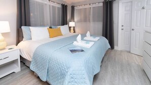 Une chambre d’hôtel comprenant un lit, des tables de chevet, une commode, une porte et une armoire.