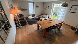 Una sala moderna con una mesa de comedor de madera, un sofá, una mesa de centro y una lámpara.