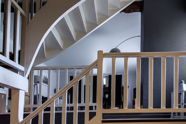 A modern interior with a spiral staircase, wooden railings, and a dark accent wall.