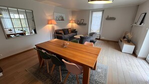 A dining area with a wooden table and chairs, a sofa, a lamp, and a window.