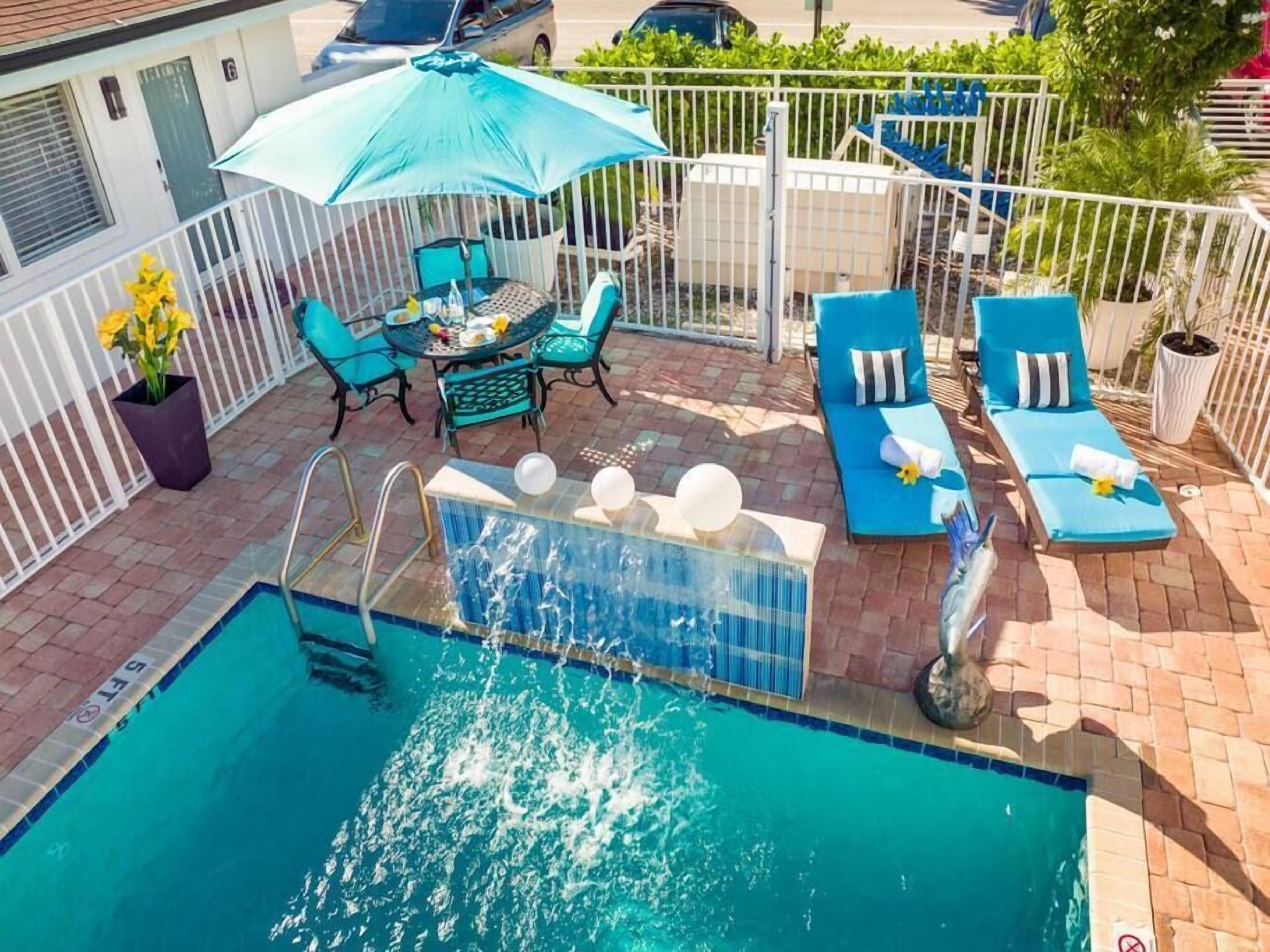 A swimming pool with a hot tub, outdoor seating, and a table with chairs.