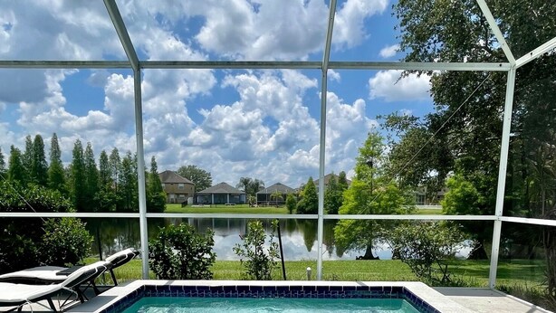 A swimming pool with a tiled edge, surrounded by a covered area with a metal frame. - Relaxing 3BED 2BATH POOL Home w. Pond View & HOT TUB (Brandon)