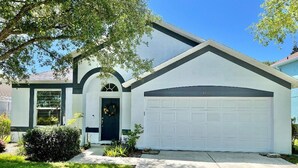A single-story house with a garage, a front door, and a small front yard with a tree and shrubs. - Relaxing 3BED 2BATH POOL Home w. Pond View & HOT TUB (Brandon)