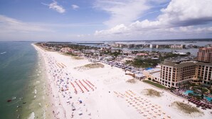 A beach resort with multiple hotel buildings, a sandy beach with umbrellas, and a marina in the background. - Relaxing 3BED 2BATH POOL Home w. Pond View & HOT TUB (Brandon)