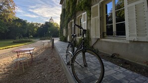 A building with a bicycle parked outside, a table and chairs, and a garden area. - LOGIS HOTEL DU PARC (Pont-a-Mousson)