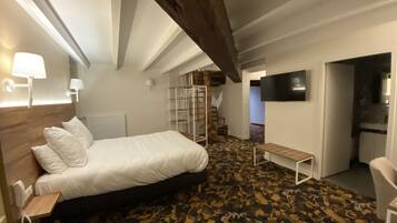 A bedroom with a bed, bedside table, lamp, and a TV mounted on the wall.