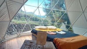 Ein gemütliches Zelt mit Bett, Tisch und Blick ins Grüne.
