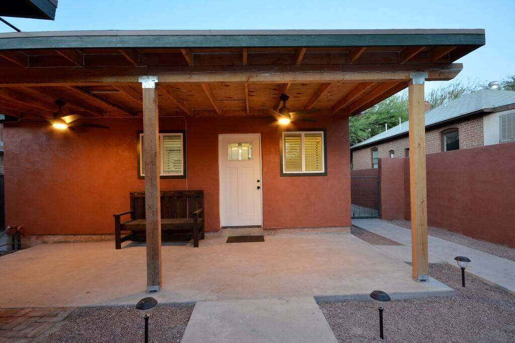 A covered outdoor area with a door, two windows with shutters, and a bench.