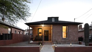 A single-story brick house with a front porch, a small attached garage, and a pathway leading to the entrance.