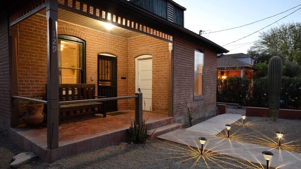 A brick house with a porch, a door, and a window.