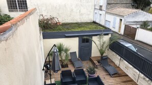 Terrassa al terrat amb mobles d'exterior, una porta i una petita zona de jardí.