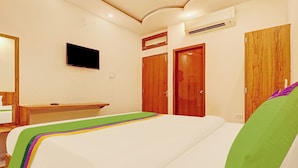 A hotel room with a bed, a television, a wooden wardrobe, and an air conditioning unit. - Treebo Silver Stallion (Lucknow)