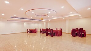 A spacious conference room with multiple tables and chairs, recessed ceiling lighting, and a central decorative light fixture. - Treebo Silver Stallion (Lucknow)