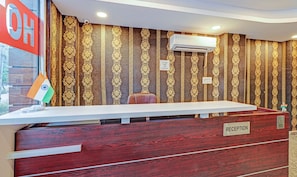 A reception desk with a "RECEPTION" sign, an air conditioning unit, and a flag of India. - Treebo Silver Stallion (Lucknow)