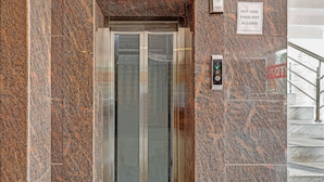 An elevator with a granite wall and a sign indicating no food allowed outside. - Treebo Silver Stallion (Lucknow)