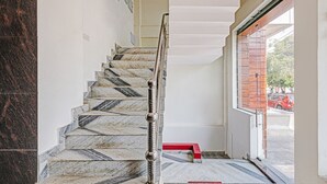 A staircase with marble steps and a metal handrail, leading to a doorway with a red baseboard. - Treebo Silver Stallion (Lucknow)