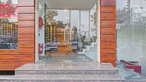 A building entrance with a glass door, wooden paneling on the sides, and a set of marble steps leading up to the door. - Treebo Silver Stallion (Lucknow)