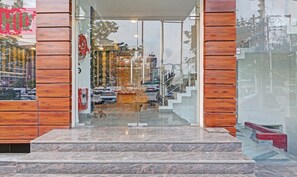 A building entrance with a glass door, wooden paneling on the sides, and a set of marble steps leading up to the door. - Treebo Silver Stallion (Lucknow)