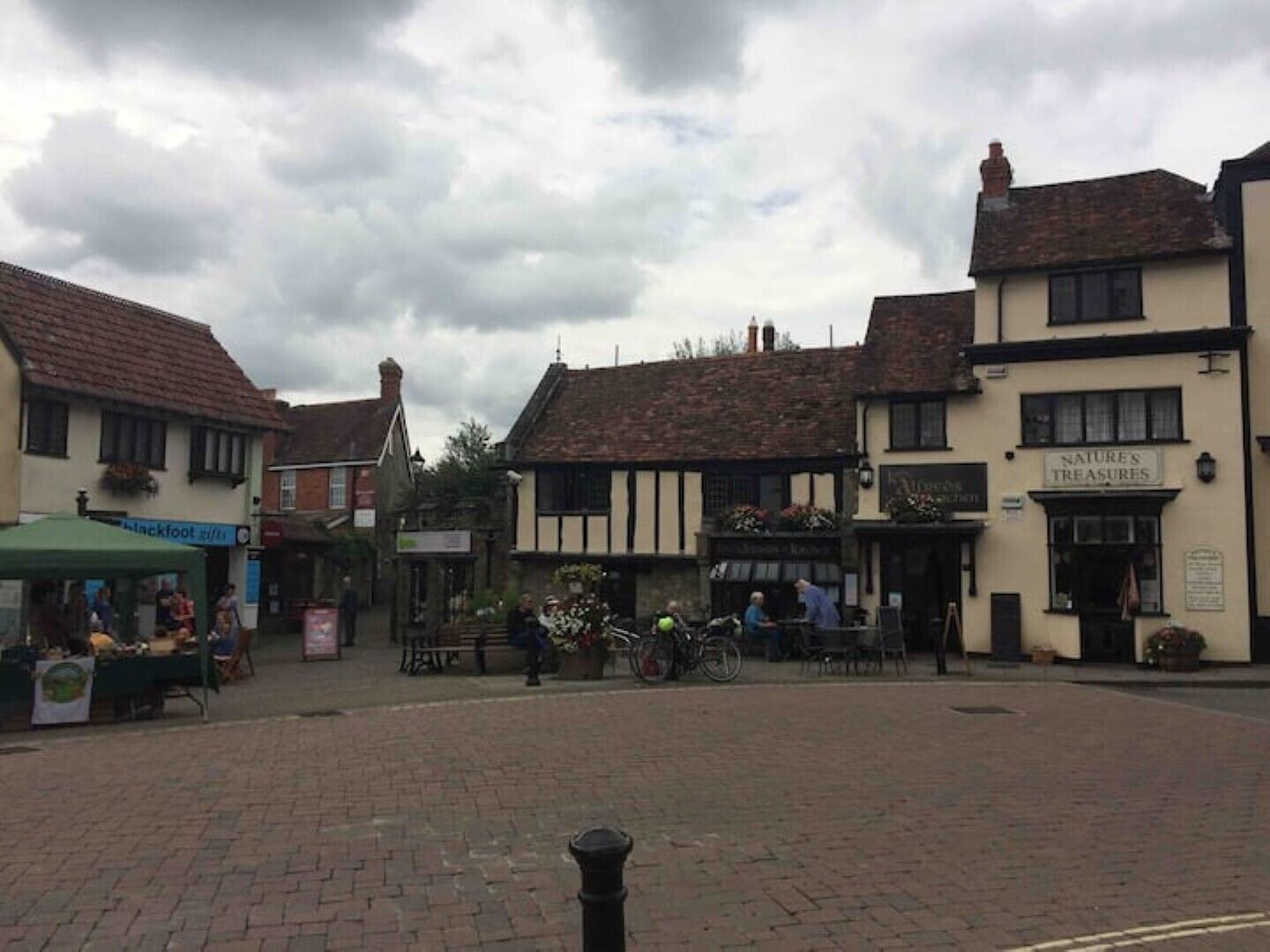 A traditional British pub with outdoor seating, a sign for 'Nature's Treasures', and a 'Blackfoot' sign visible in the background.