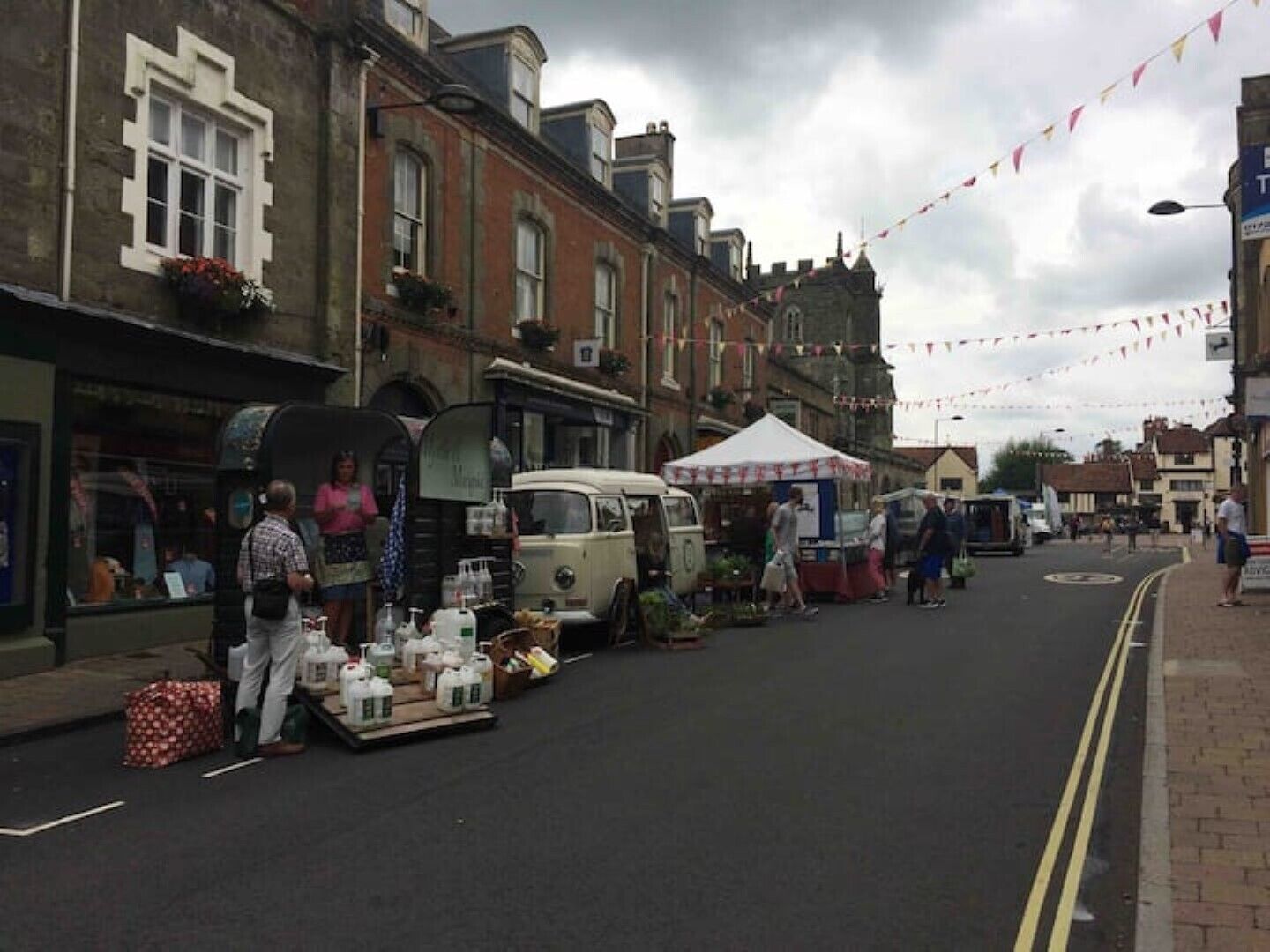 A street market with stalls and a vintage car.