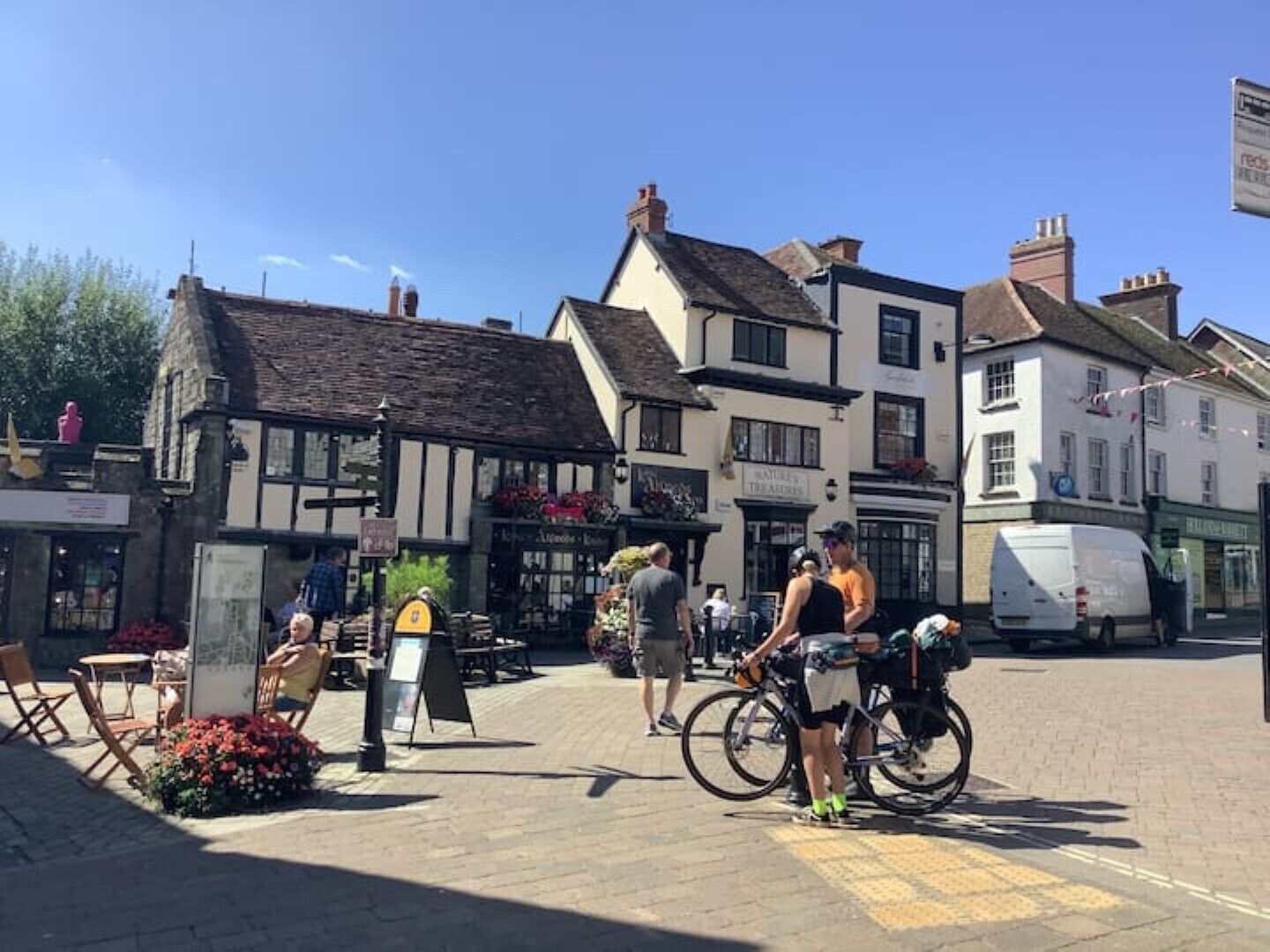 A traditional European town square with historic buildings, outdoor seating, and bicycles.