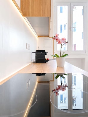 A modern kitchen with a built-in oven, a small countertop, and a potted orchid.