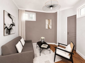 A living room with a sofa, a chair, a coffee table, and artwork on the walls.