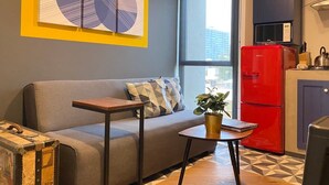 Ein modernes Wohnzimmer mit einem grauen Sofa, einem kleinen Holztisch und einem roten Kühlschrank.