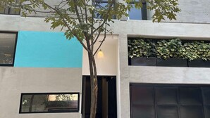 Ein modernes Gebäude mit Baum davor, einer Garagentür und einer blauen Wand.
