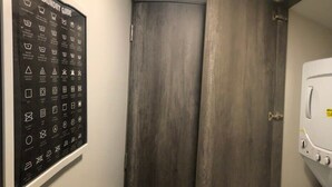Ein Waschraum mit einer an der Wand befestigten Wäscheanleitung, einer geschlossenen Tür und einer weißen Waschmaschine.