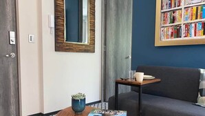A modern living room with a grey sofa, a small wooden table with a magazine, a blue vase, and a wall-mounted bookshelf. - Excelente Apto con Terraza Pegado a la Condesa (Ciudad de México)