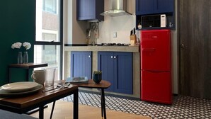 A compact kitchen with blue cabinets, a red refrigerator, and a patterned floor. - Excelente Apto con Terraza Pegado a la Condesa (Ciudad de México)
