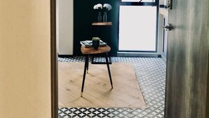 A hallway with a tiled floor, a door labeled '6', a small table with a plant, and a wall-mounted skull decoration. - Excelente Apto con Terraza Pegado a la Condesa (Ciudad de México)