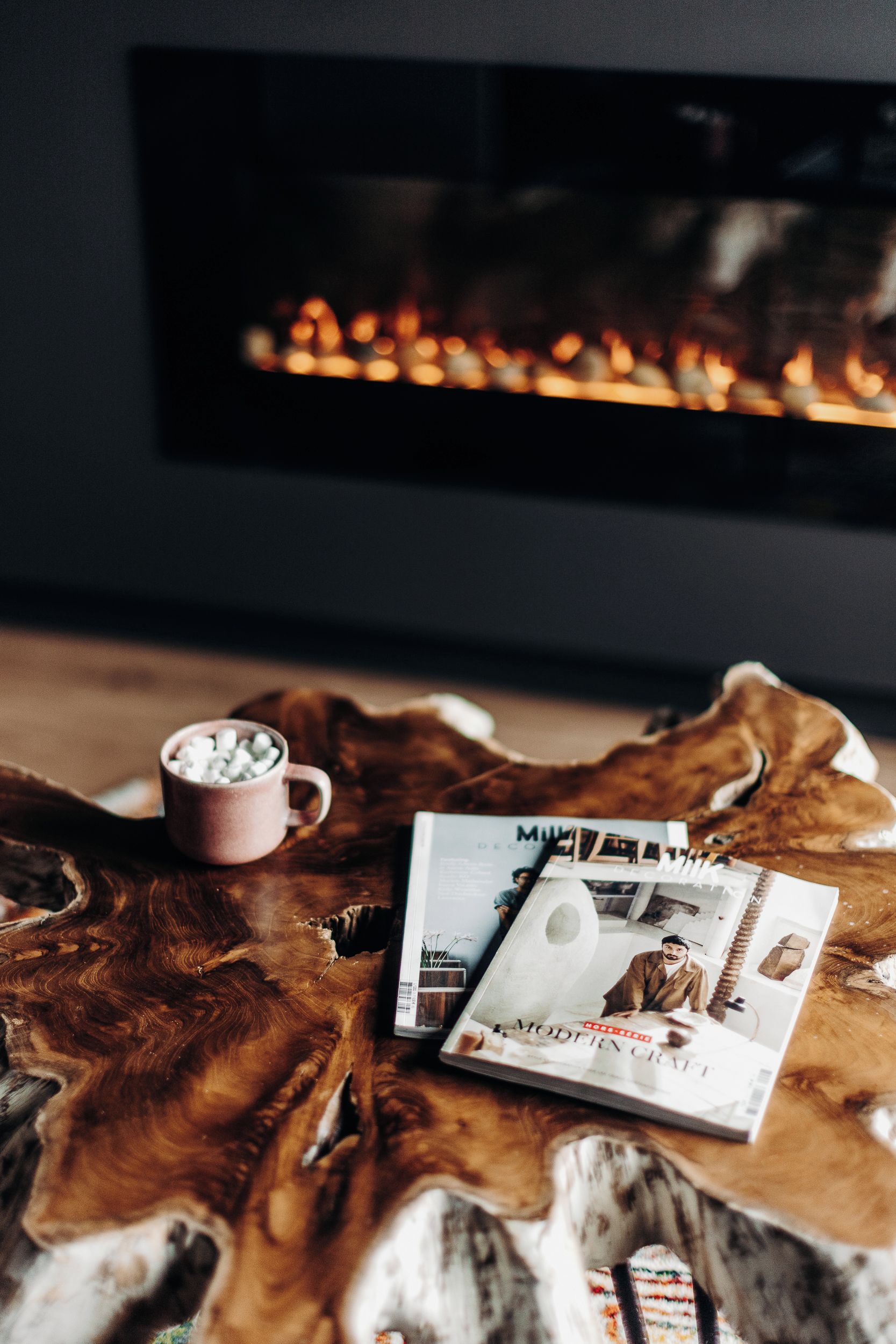 Una revista sobre una superficie de madera con una chimenea al fondo.