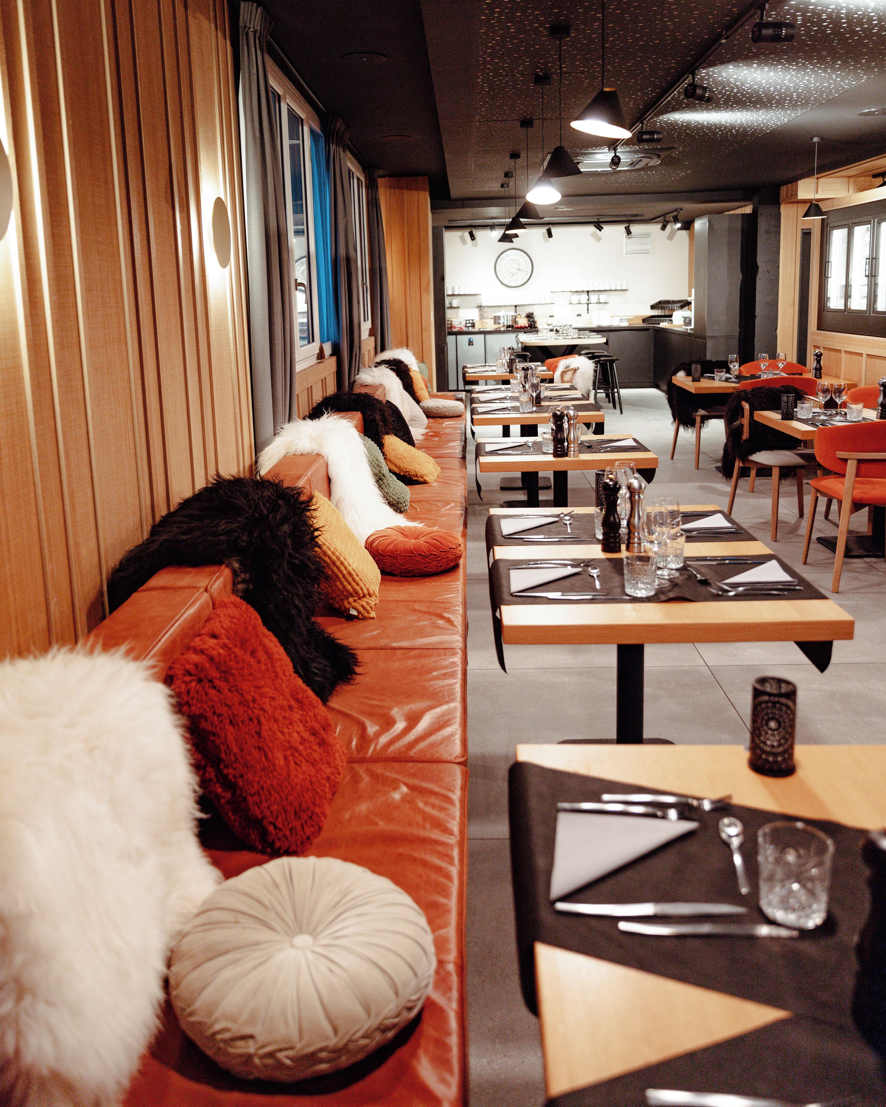 En restaurant med lange fællesspisesteder, polstrede siddepladser og et moderne interiørdesign.