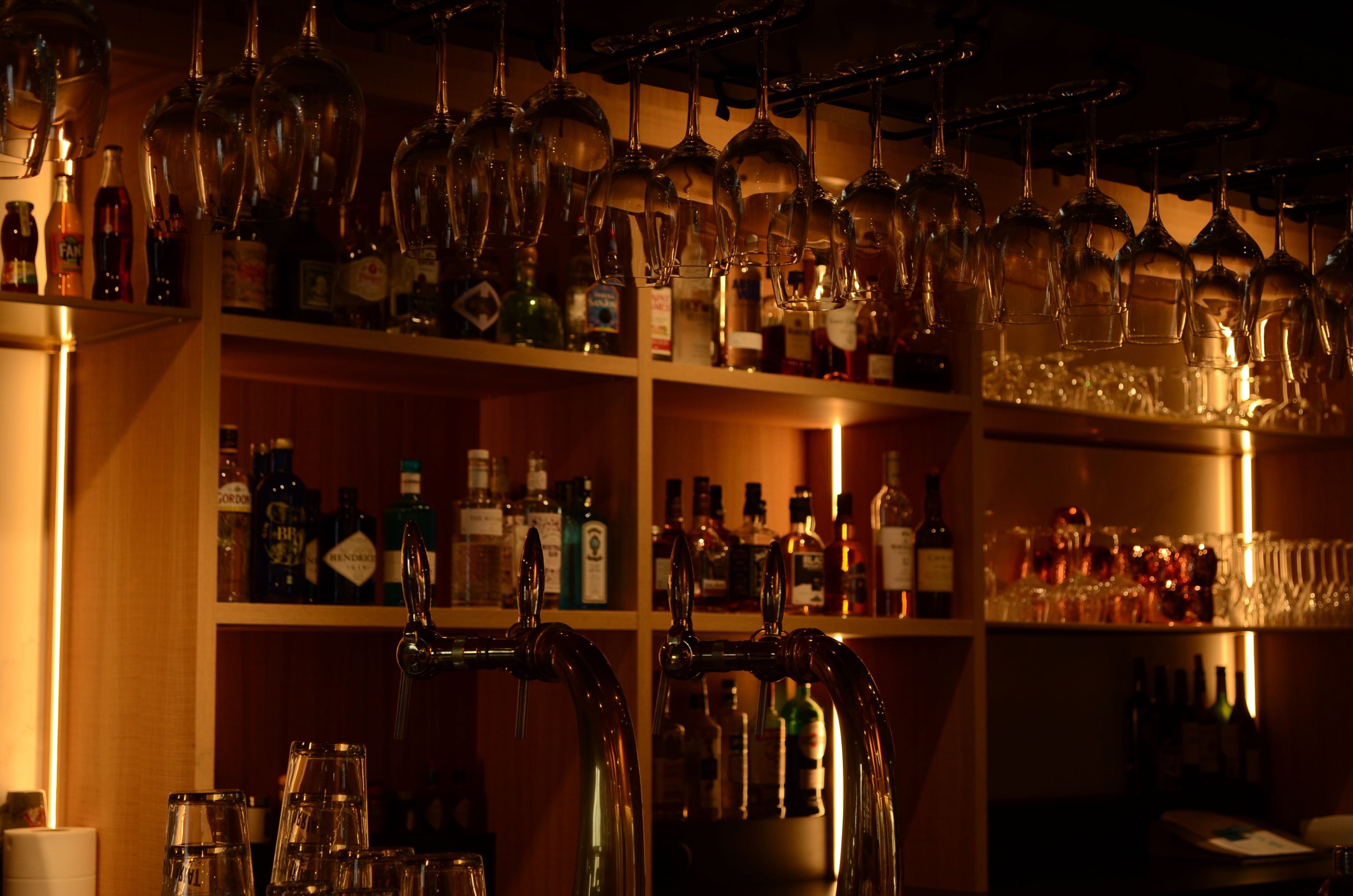 Zona de bar con estantes llenos de botellas y vasos.