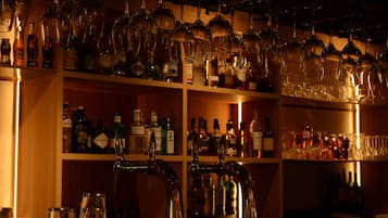 Zona de bar con estantes llenos de botellas y vasos.