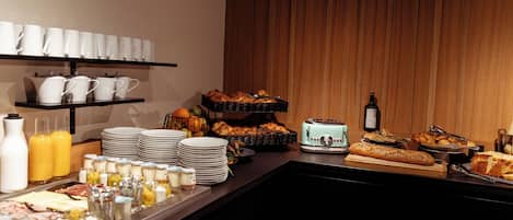 A buffet with various food items, including bread, pastries, and beverages.