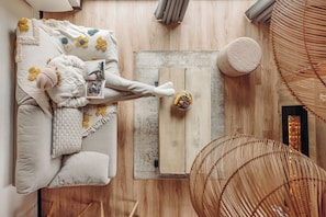 A top-down view of a cozy room with a bed, a wooden floor, a small table with a fruit bowl, and a woven chair. - Iskö Chalets-hötel (Eaux-Bonnes)