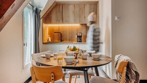 A modern kitchen with wooden cabinetry, a dining table with chairs, and a breakfast setting. - Iskö Chalets-hötel (Eaux-Bonnes)