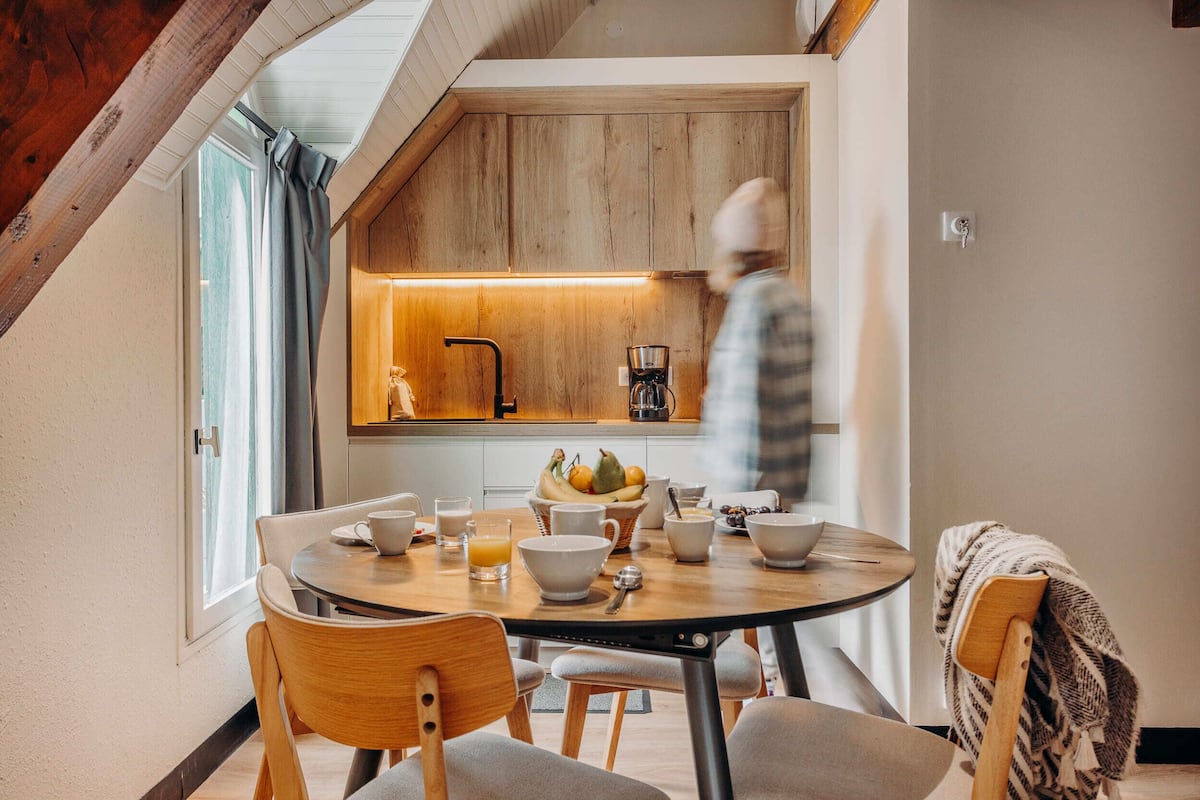 A modern kitchen with wooden cabinetry, a dining table with chairs, and a breakfast setting.