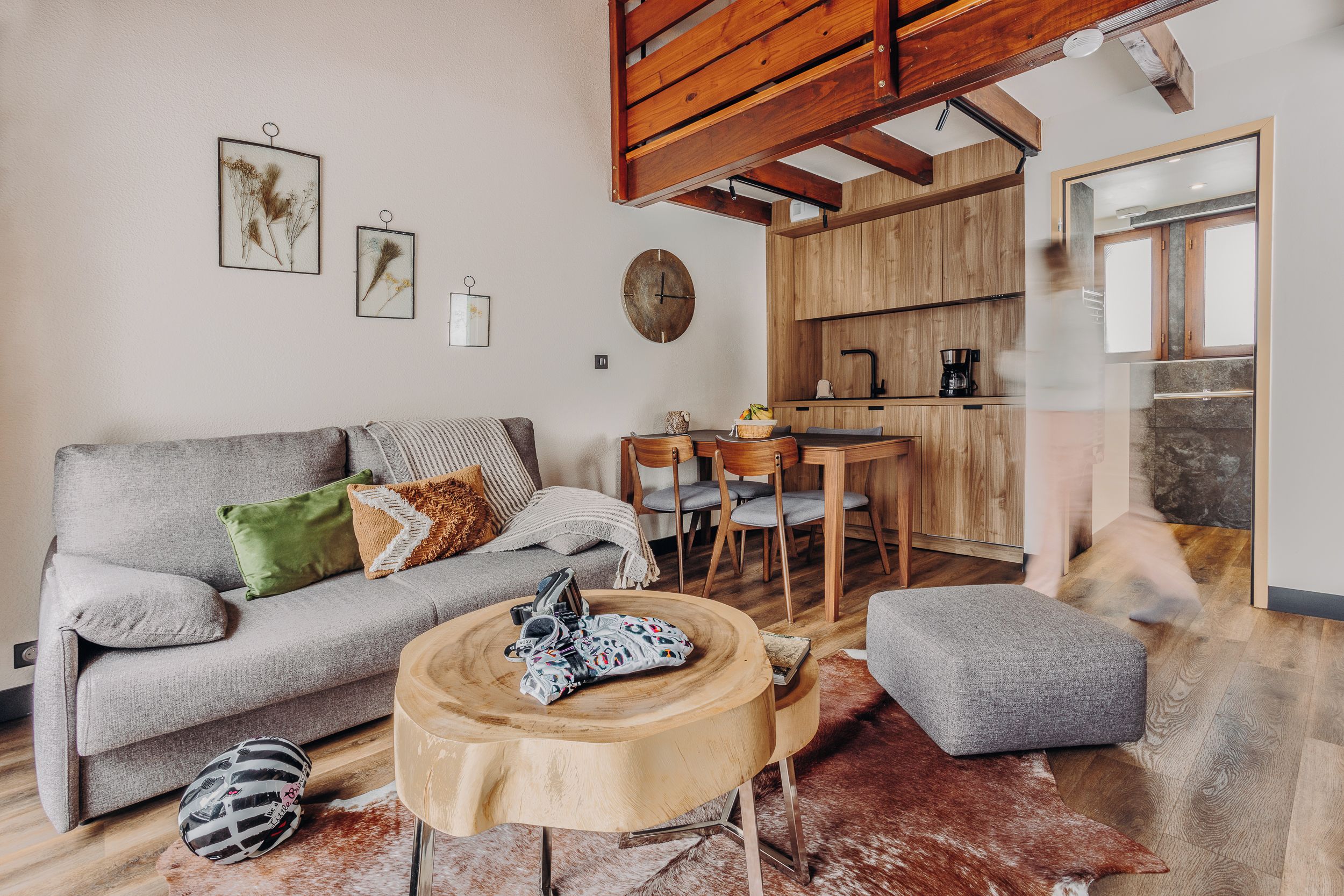 A cozy living room with a grey sofa, a round wooden coffee table, and a rustic rug.