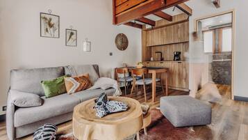 A cozy living room with a grey sofa, a round wooden coffee table, and a rustic rug.