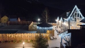 A nighttime view of a residential area with houses, a wooden fence, and a building with blue lights. - Iskö Chalets-hötel (Eaux-Bonnes)