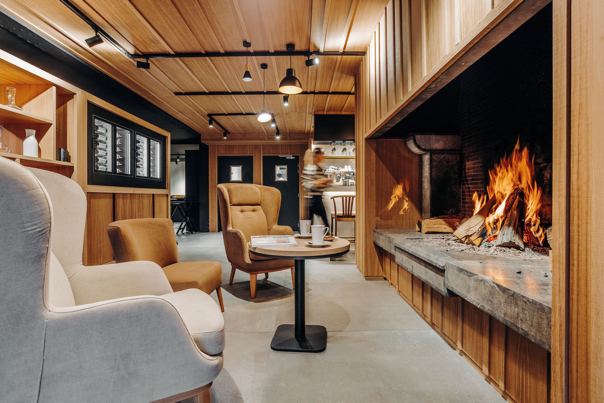 A cozy interior with a fireplace, wooden ceiling, and comfortable seating.
