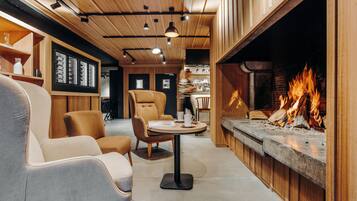 A cozy interior with a fireplace, wooden ceiling, and comfortable seating.