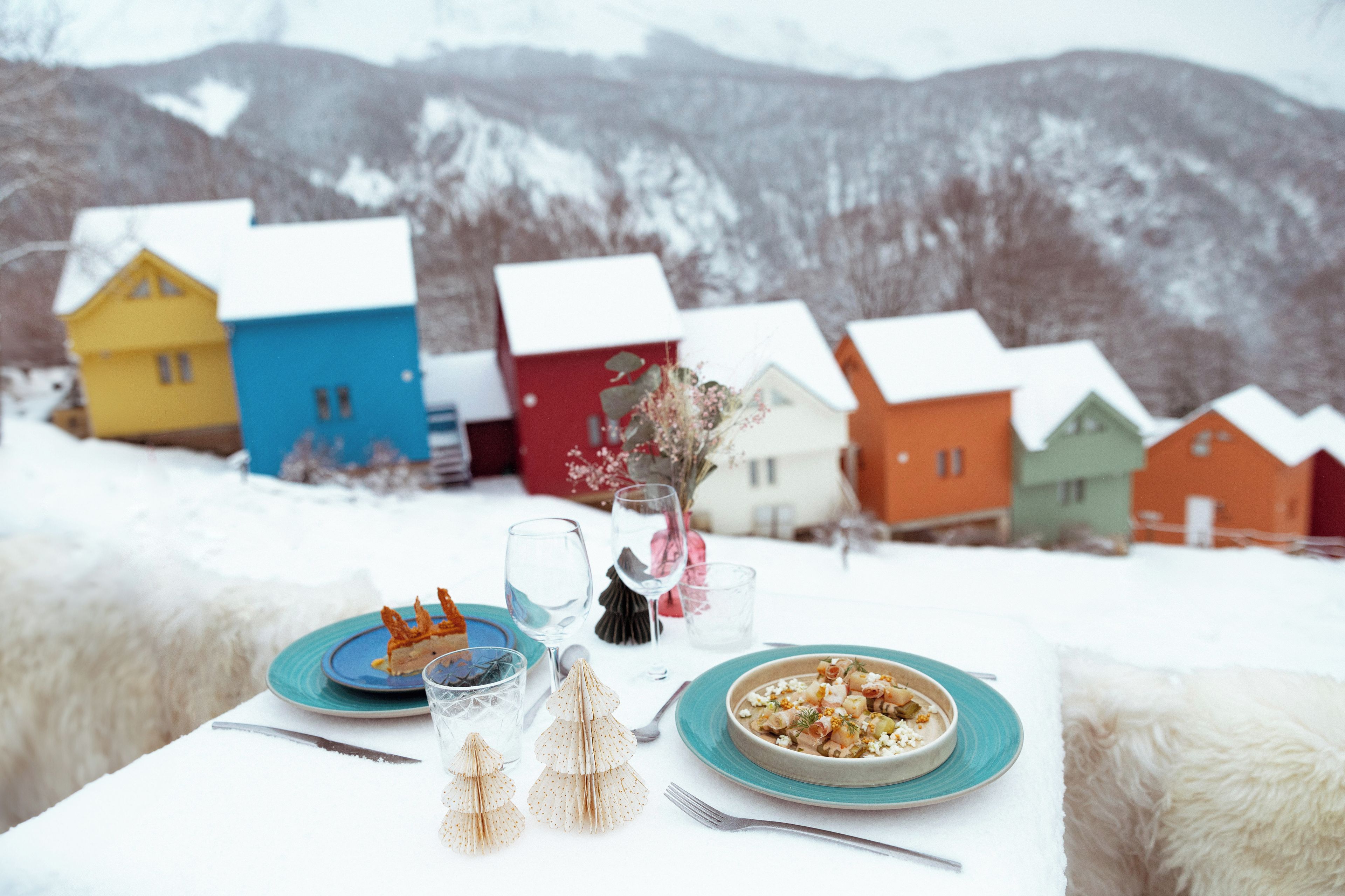 A table set with plates, glasses, and cutlery, with a bowl of food and a vase of flowers.