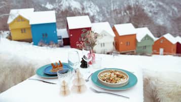 A table set with plates, glasses, and cutlery, with a bowl of food and a vase of flowers.